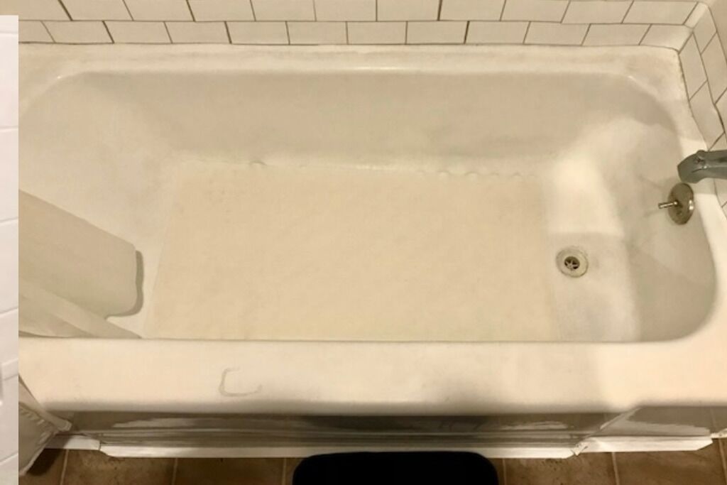 Une baignoire équipée d’un drain, d’un robinet et d’une pomme de douche.