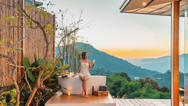 A person sitting on a wooden deck with a view of a mountainous landscape. - Baan La Ong Fah 2-Mon Jam (Mae Rim)