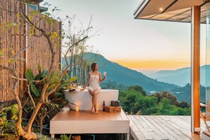 A person sitting on a wooden deck with a view of a mountainous landscape. - Baan La Ong Fah 2-Mon Jam (Mae Rim)