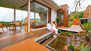 A modern house with a wooden deck, a glass-enclosed room, and a small pond. - Baan La Ong Fah 2-Mon Jam (Mae Rim)