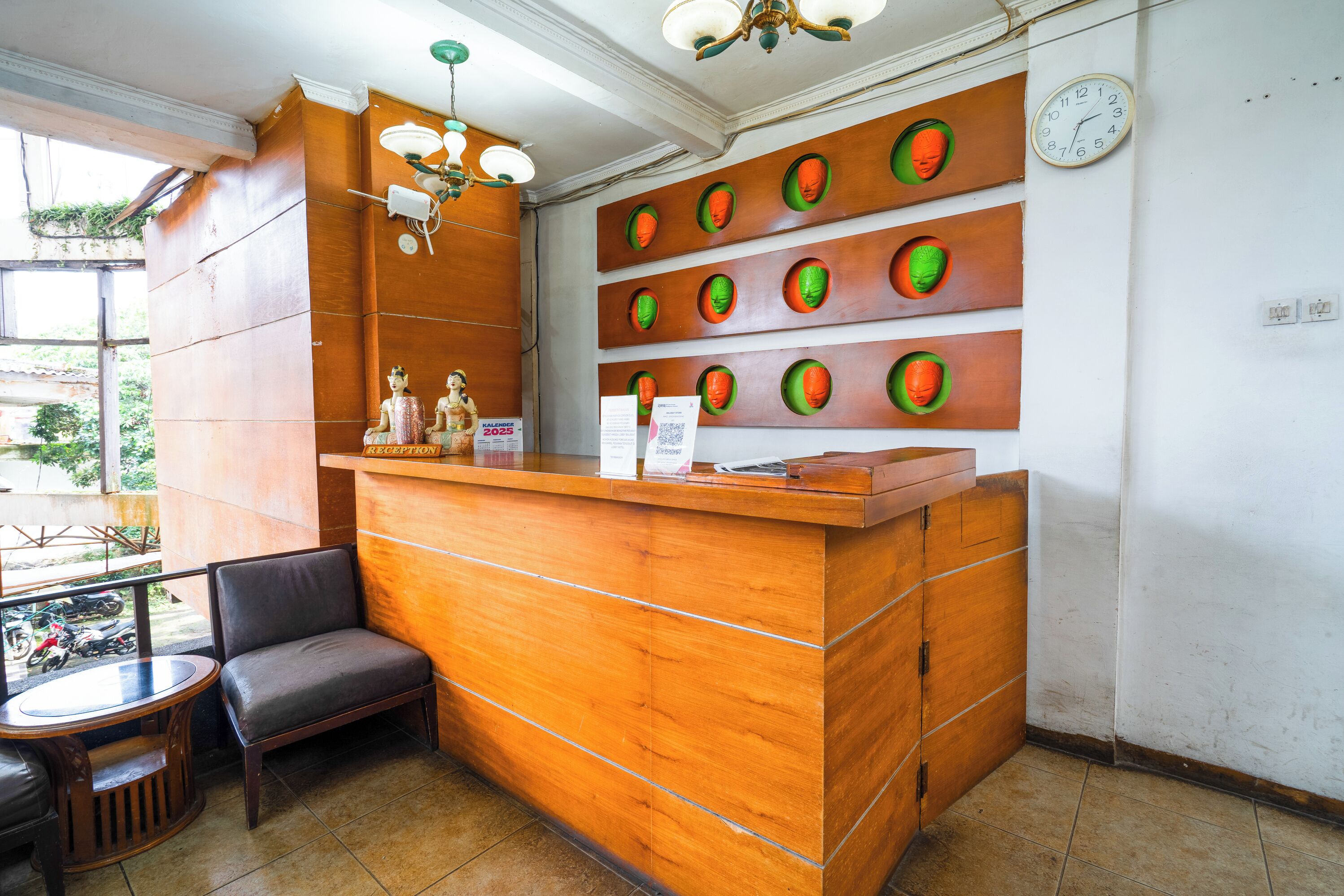 Balcão de atendimento com acabamento em madeira, área de estar com um banco e parede com recortes circulares.