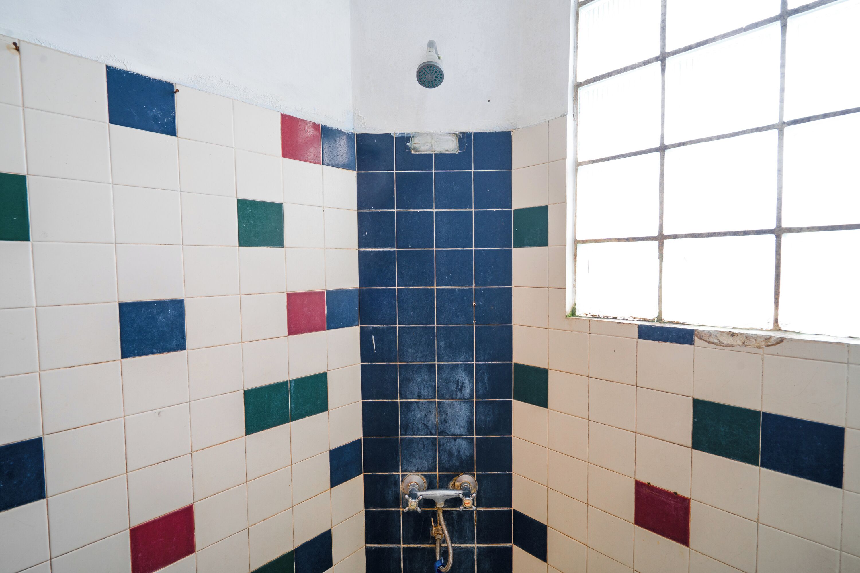 A bathroom with a tiled wall featuring a mix of white, blue, and red tiles.
