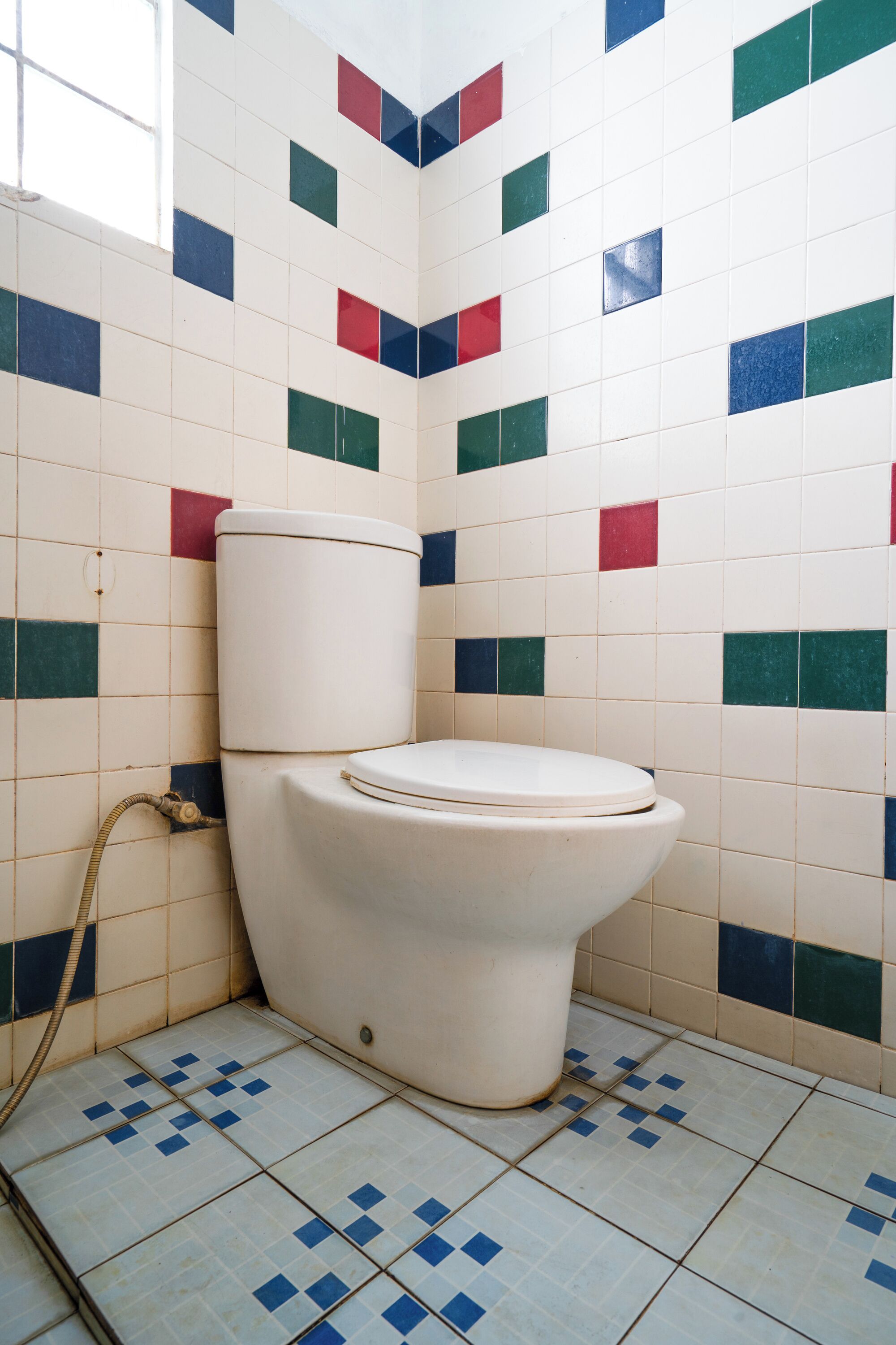 Un baño con inodoro, paredes y suelo de baldosas.