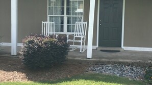 A house with a covered porch, a front door, and a small bush.