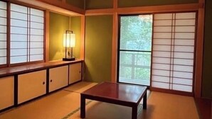 Perinteinen japanilainen huone, jossa on tatamimatto, paperiset shoji-liukuovet ja matala puupöytä.