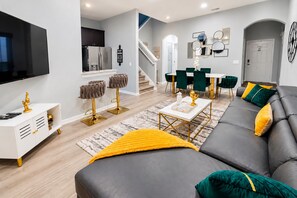 A modern living room with a sofa, coffee table, and a TV. There is a staircase leading to another level.