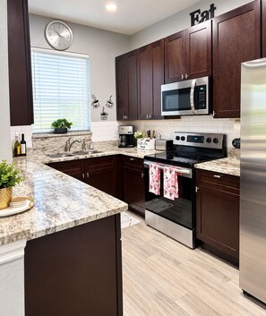 Una cocina moderna con armarios de madera oscura, electrodomésticos de acero inoxidable y encimera de mármol.