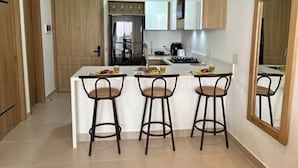 A modern kitchen with a central island, bar stools, and wooden cabinets. - Cartagena Baia Kristal | Perfect Escape Kabo 1-Apt 2 F (Cartagena de Indias)