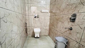 A bathroom with a toilet, a hand dryer, and a trash bin. - Hotel Hare Krishna Dham (Mathura)
