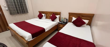 A hotel room with two wooden beds, each with white and red bedding, a wooden nightstand, and a grey patterned curtain.