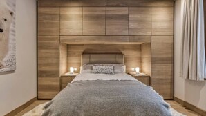 Ein Schlafzimmer mit einem Holzkopfteil, einem großen Bett, zwei Nachttischen mit Lampen und einem flauschigen Teppich.