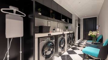 A modern laundry area with a checkered floor, a washing machine, a drying rack, and a small table with chairs.