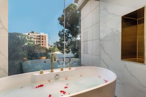 A modern bathroom with a freestanding bathtub, marble walls, and a view of a cityscape. - XANA Deluxe International Hotel Dongshankou Metro Station Branch (Guangzhou)