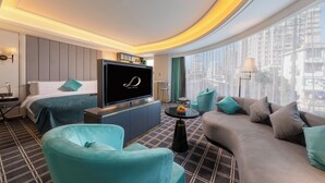 Ein modernes Hotelzimmer mit einem großen Bett, einer Couch, einem Fernseher und Blick auf die Stadt.