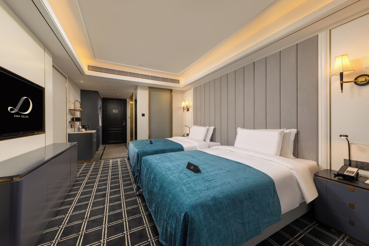 Habitación de hotel con dos camas, televisión, escritorio y minibar.