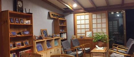 Una habitación acogedora con muebles de madera, una estantería, una mesa con tazas y un jarrón, y una ventana con vistas.