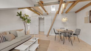 Un salon moderne avec un canapé, une table à manger et des chaises. Un escalier mène à un niveau supérieur.