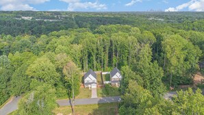 A residential area with two houses surrounded by dense forest.
