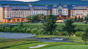 Un hotel grande con varias edificaciones, un campo de golf y un lago.
