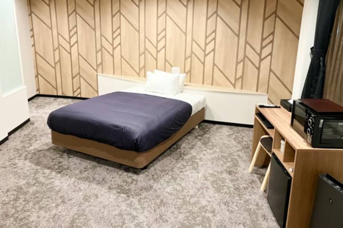 Une chambre d’hôtel avec un lit, un bureau doté d’un micro-ondes et un mur orné d’un motif géométrique.