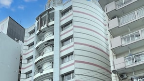 A multi-story building with a curved facade, balconies, and a clear sky. - HOTEL LiVEMAX Naha Naminoue I (Naha)