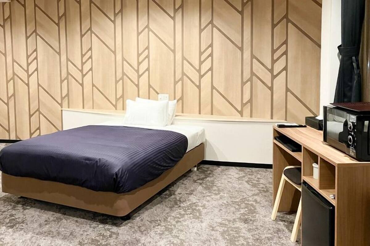 Une chambre d’hôtel avec un lit, un bureau doté d’un micro-ondes et un mur orné d’un motif géométrique.