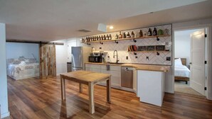 A modern kitchen with wooden flooring, white cabinets, and a wooden dining table. - Lakefront Retreat w/ Private Dock & Fire Pit (Rathdrum)