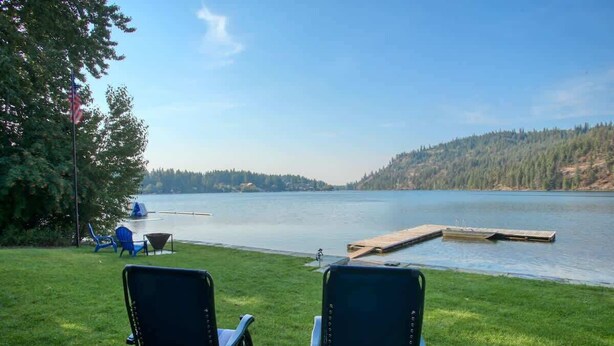 A lakeside view with two chairs facing the water, a dock, and a flagpole. - Lakefront Retreat w/ Private Dock & Fire Pit (Rathdrum)