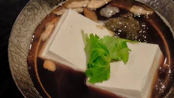 Un bol de soupe contenant du tofu, des champignons et garni de feuilles vertes.