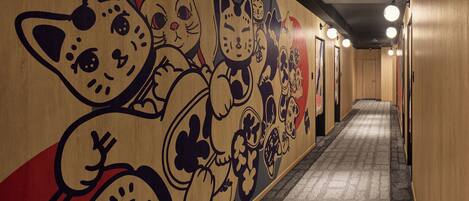 A hallway with a mural of cartoon cats and a carpeted floor.