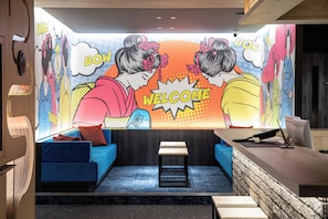 A room with a blue sofa, a small wooden table, and a reception desk. - Nagoya HOTEL HOQA Hanaironoyu (Nagoya)