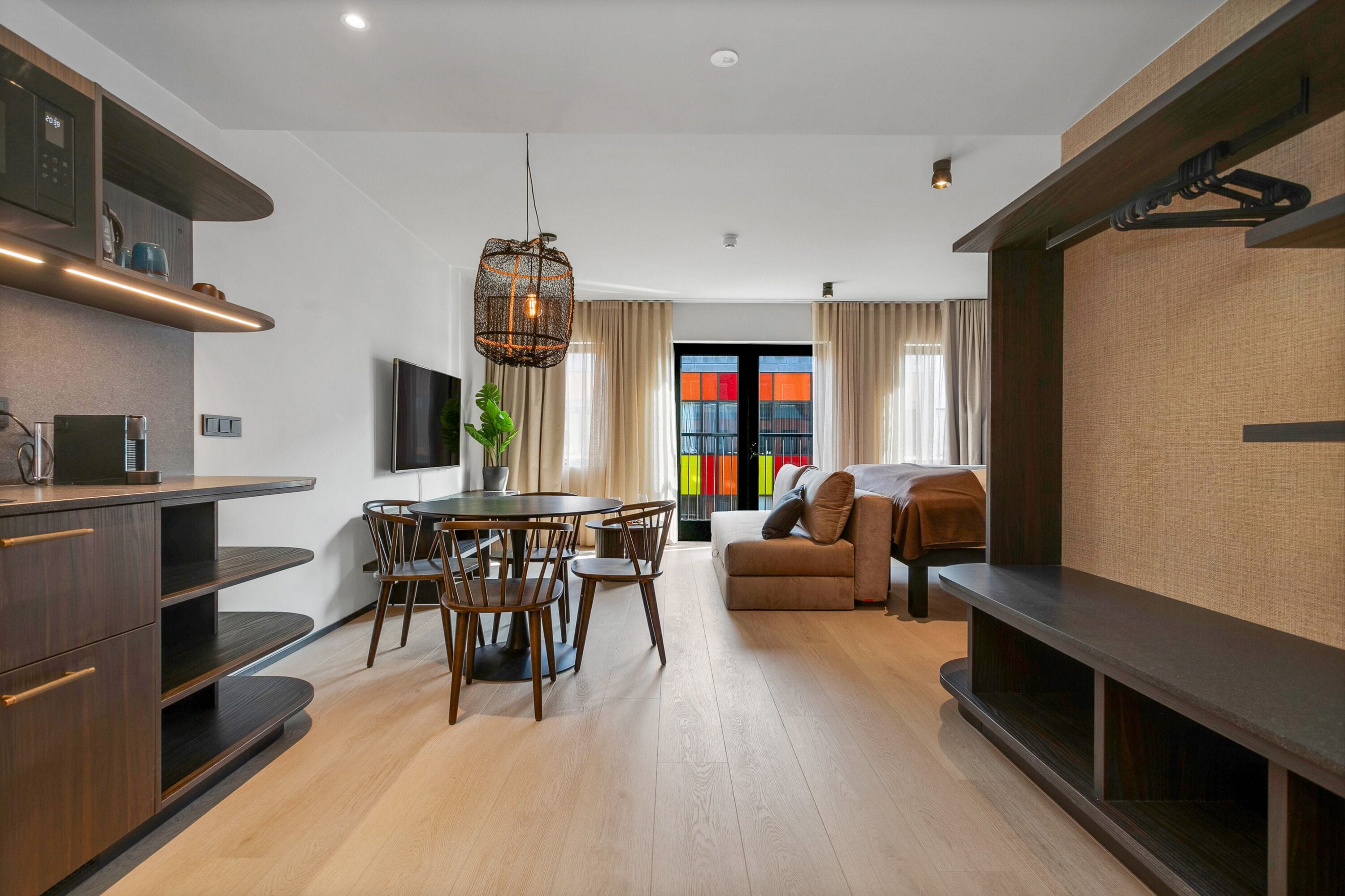 A modern living room with a dining area, a sofa, and a TV mounted on the wall.