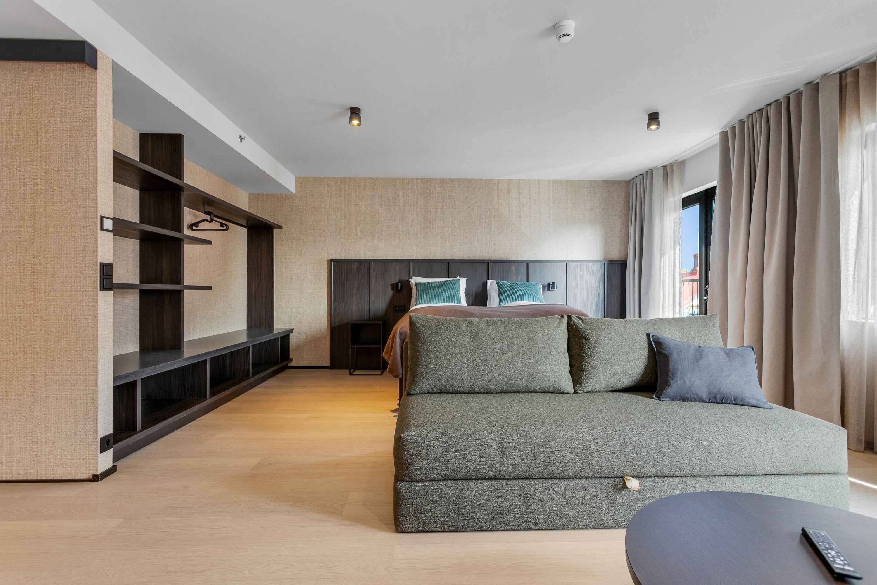 Une chambre d’hôtel moderne dotée d’un grand lit, d’un canapé, d’une télévision et d’une bibliothèque intégrée.