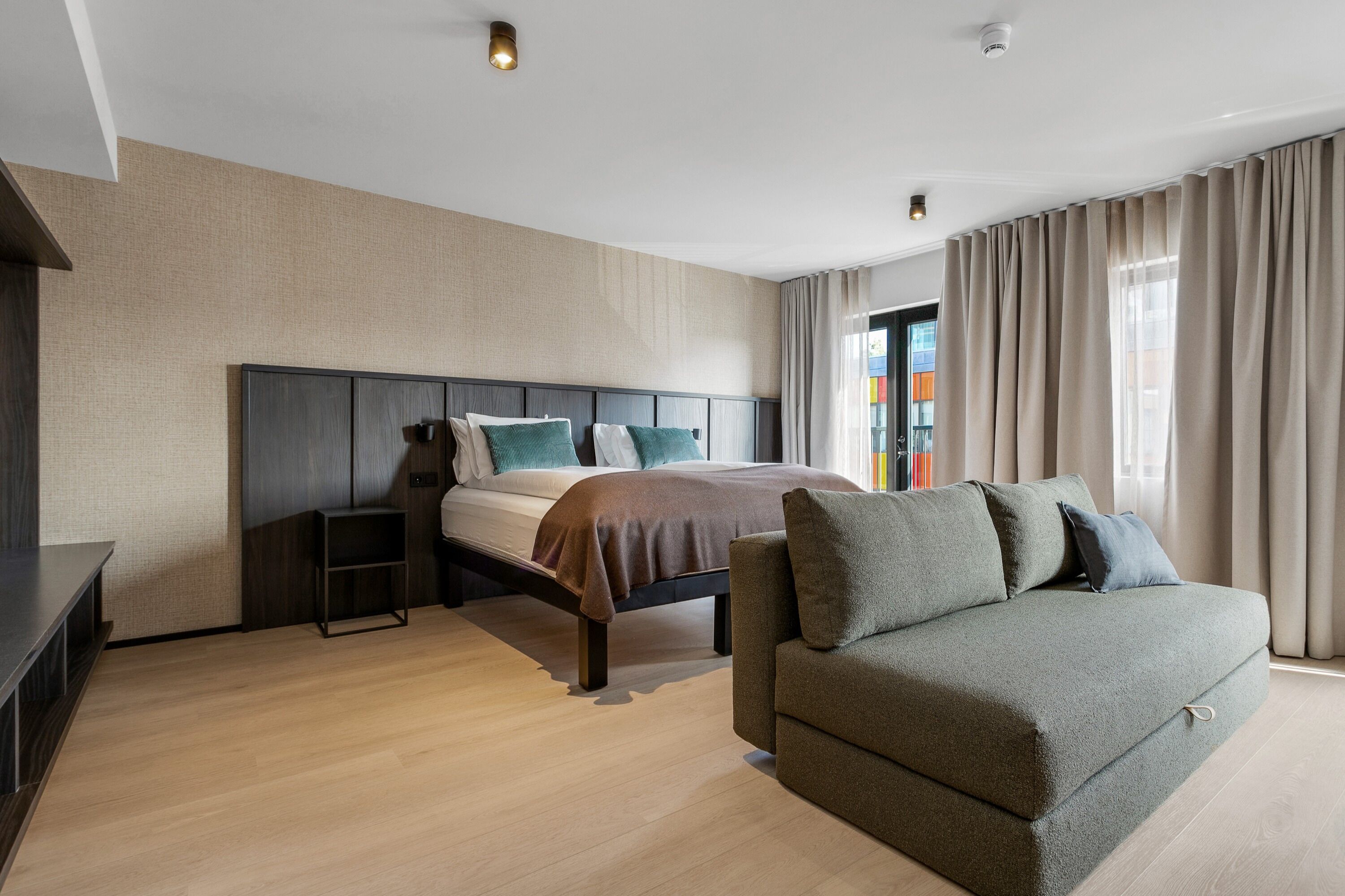 A modern bedroom with a bed, a sofa, and a TV stand.