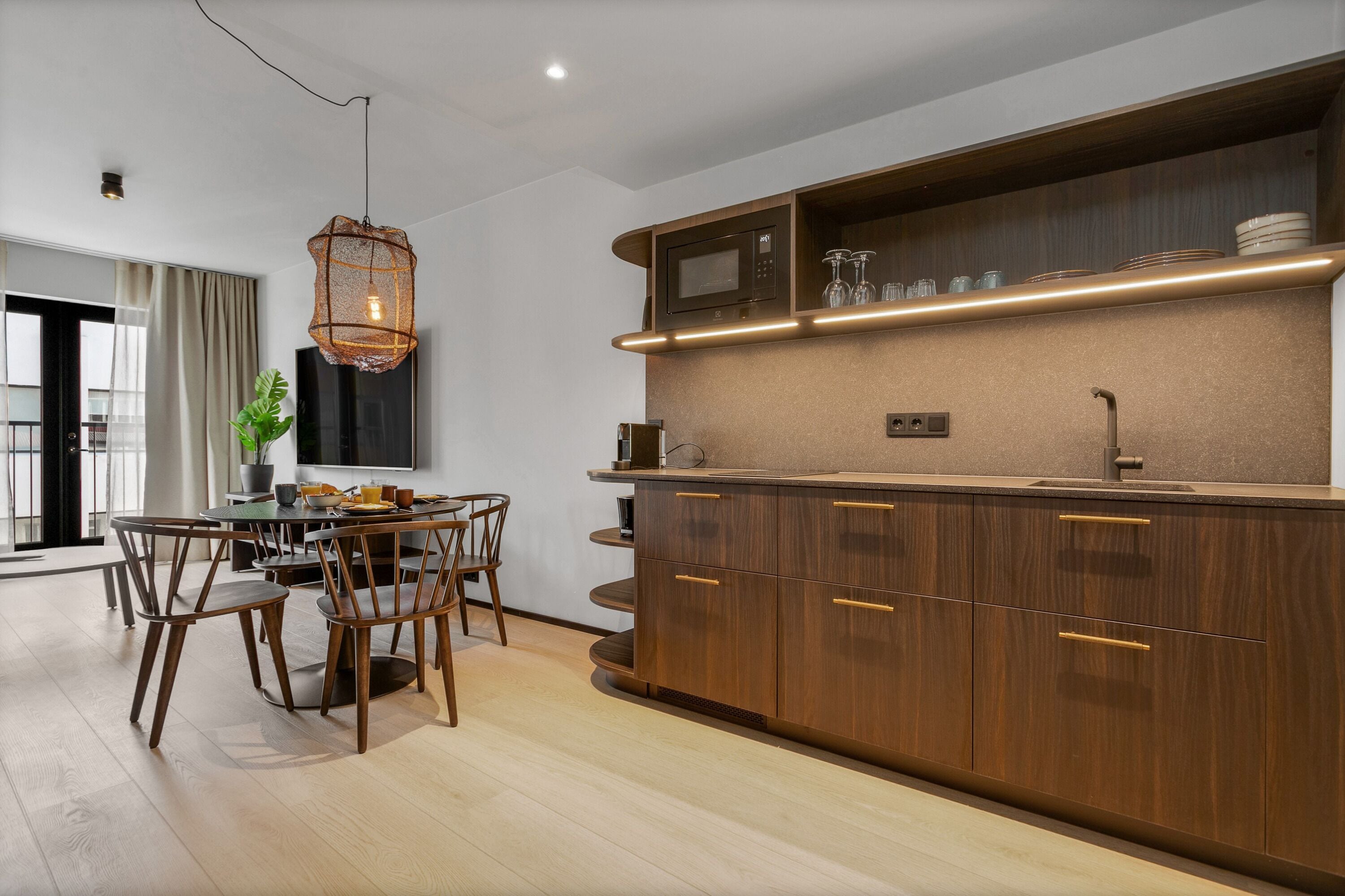 Una cocina moderna con armarios de madera, microondas integrado y un comedor con mesa y sillas.