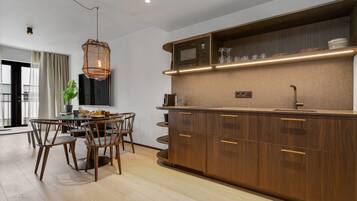 A modern kitchen with wooden cabinets, a built-in microwave, and a dining area with a table and chairs.