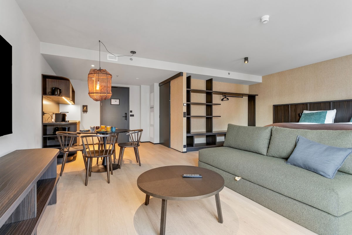 A modern living room with a sofa, a round coffee table, and a dining area with chairs and a table.