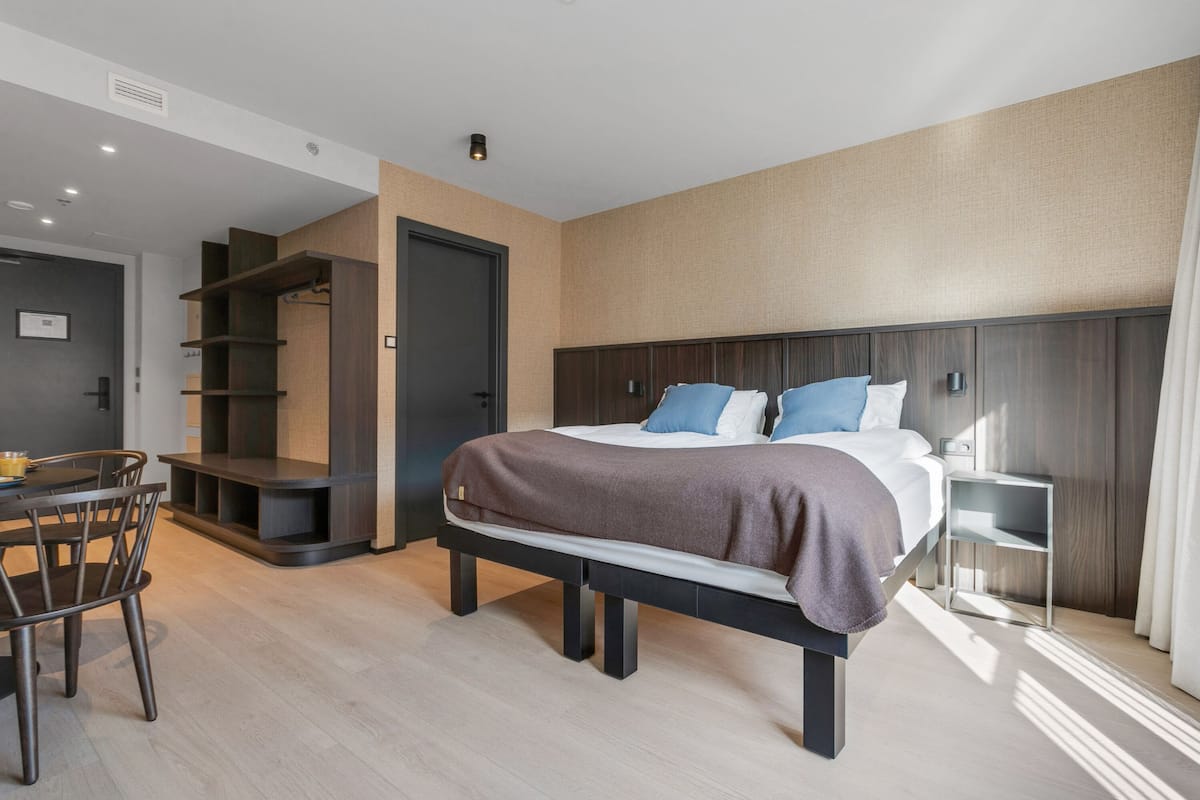 A modern hotel room with a large bed, a desk, and a seating area.