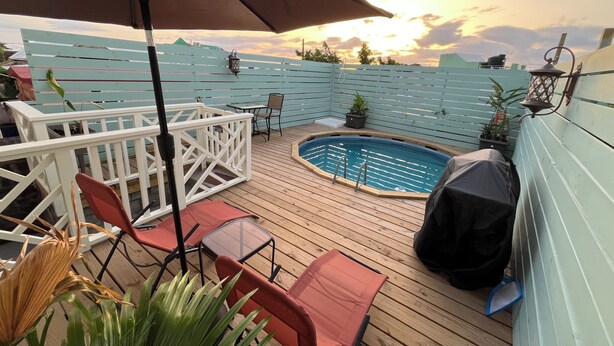 A wooden deck with a pool, outdoor furniture, and a covered area with an umbrella. - Casita Heliconia- Jr. Suite#3 (Roseau)
