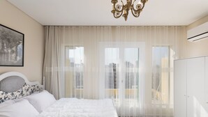 Une chambre à coucher avec un lit, des rideaux, un lustre et une vue sur la ville.