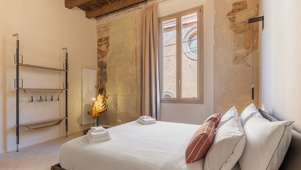 A bedroom with a bed, a radiator, a window with curtains, and a wall-mounted shelf. - Ciao Bologna Collection - San Martino (Bologna)