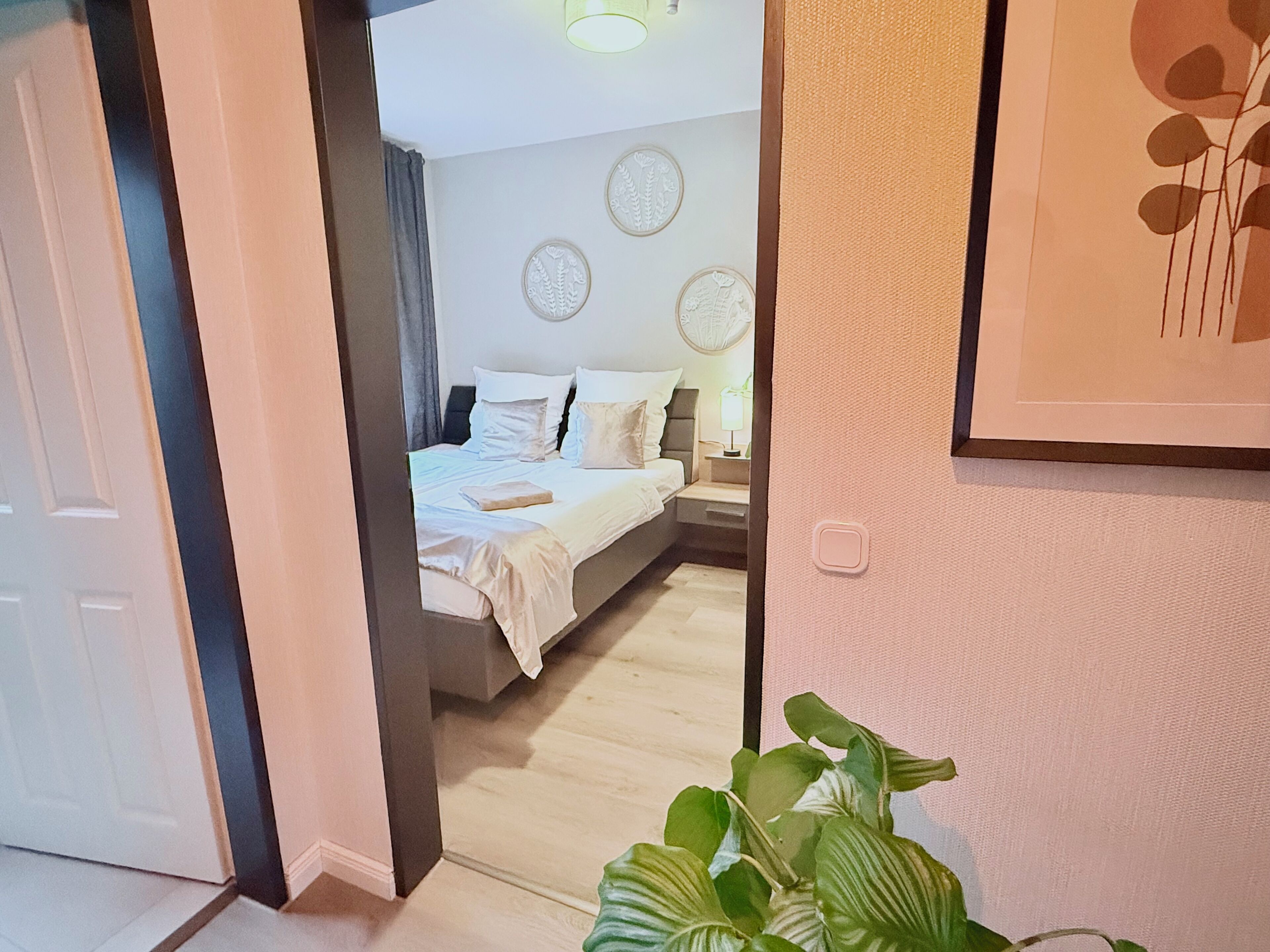 A hotel room with a bed, bedside table, lamp, and decorative wall art.