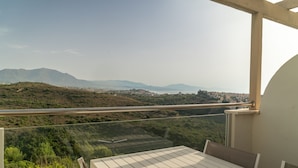 A balcony with a view of a coastal landscape, including hills and a distant city. - Modern Apartment with Sea & Mountain Views – Small Oasis, Manilva (Manilva)