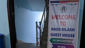 A welcome sign for Haor Bilash Guest House, indicating amenities like 18 AC/Non AC rooms, hot water, WiFi, free parking, and a dining facility. - Haor Bilash Guest House (Sunamganj)
