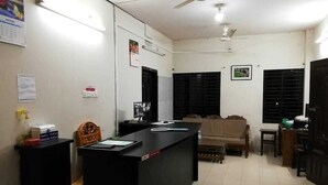 A reception area with a desk, chairs, a sofa, and a ceiling fan. - Haor Bilash Guest House (Sunamganj)