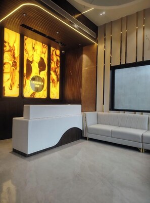 Ein modernes Interieur mit einem weißen Empfangstresen, einem grauen Sofa und einer großen Bildschirmwand.