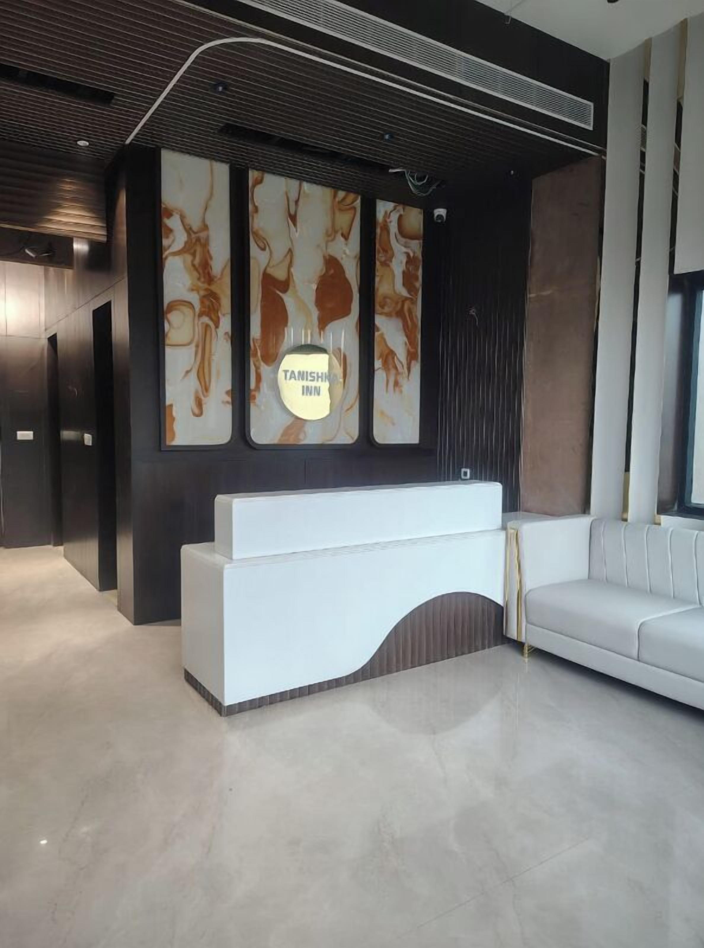 A modern reception area with a white reception desk, a sofa, and abstract wall art.