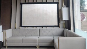 Un salon moderne avec un canapé d’angle, un grand téléviseur à écran plat fixé au mur et une fenêtre donnant sur l’extérieur.