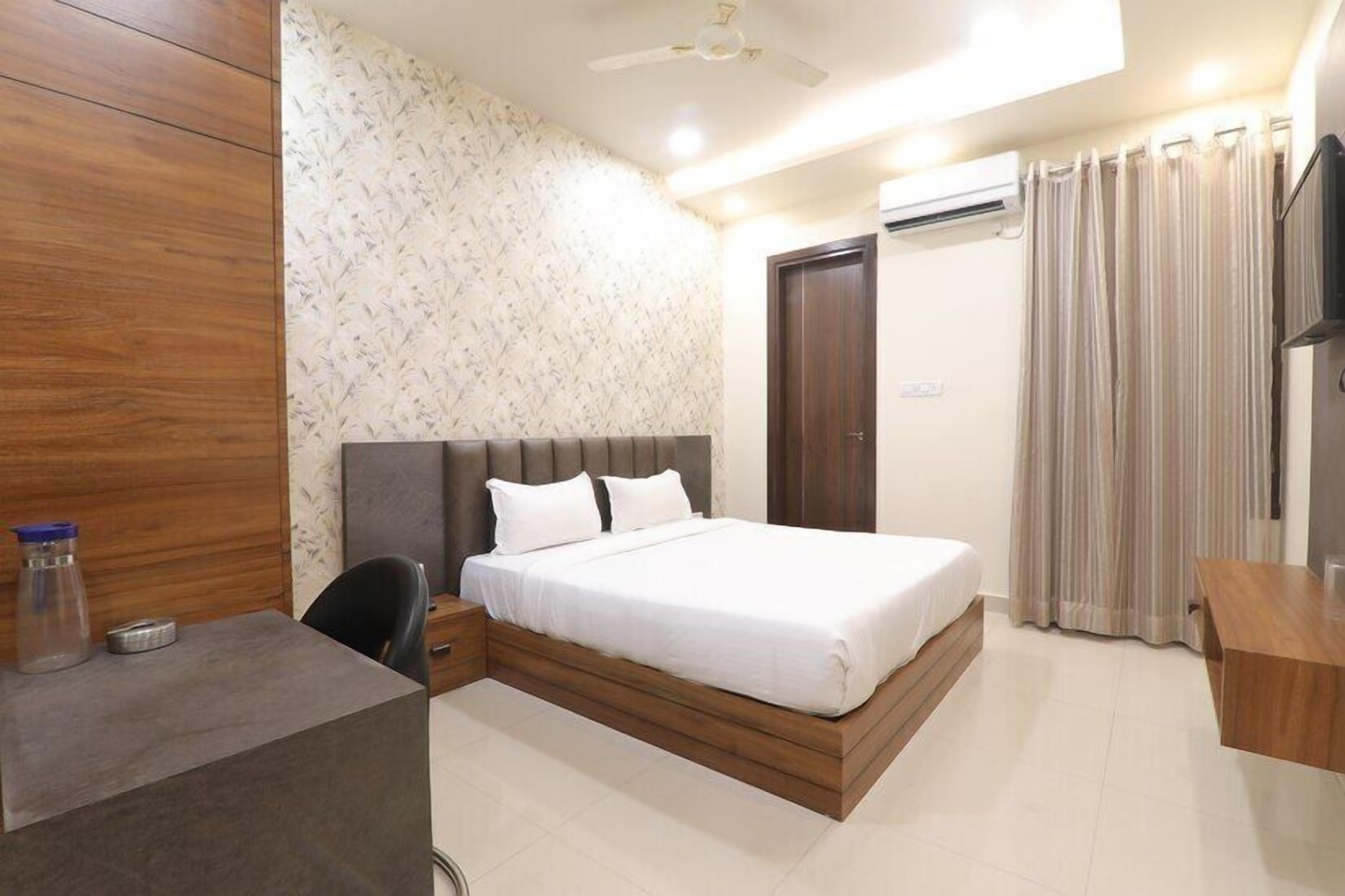 A bedroom with a bed, a desk, a chair, a wardrobe, and a ceiling fan.