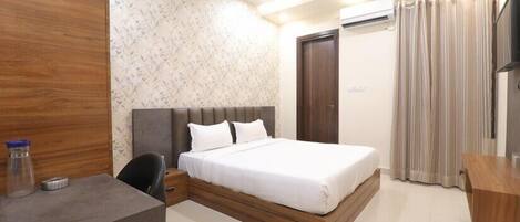 A bedroom with a bed, a desk, a chair, a wardrobe, and a ceiling fan.